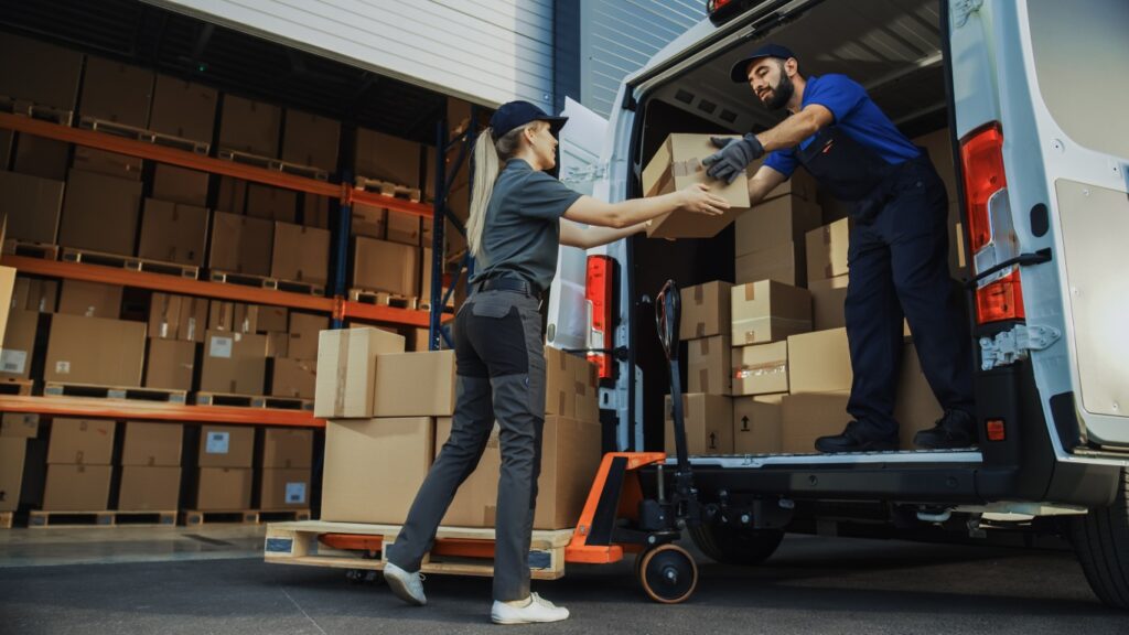 a man unloading the back of a cargo van to a woman on the street